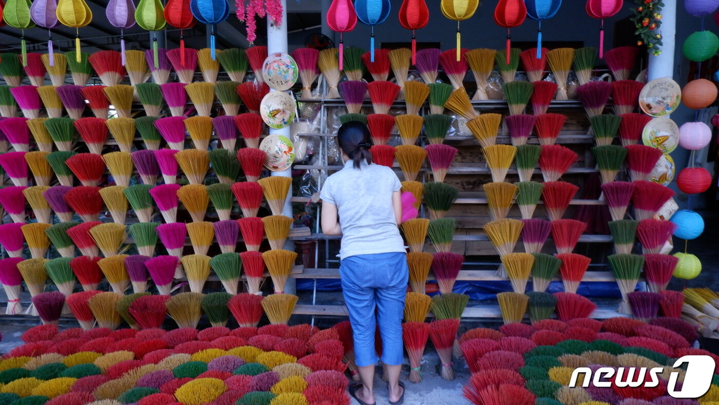 본문 이미지 - 향을 입힐 대나무를 색에 맞춰 분류하고 있는 마을 주민의 모습ⓒ News1