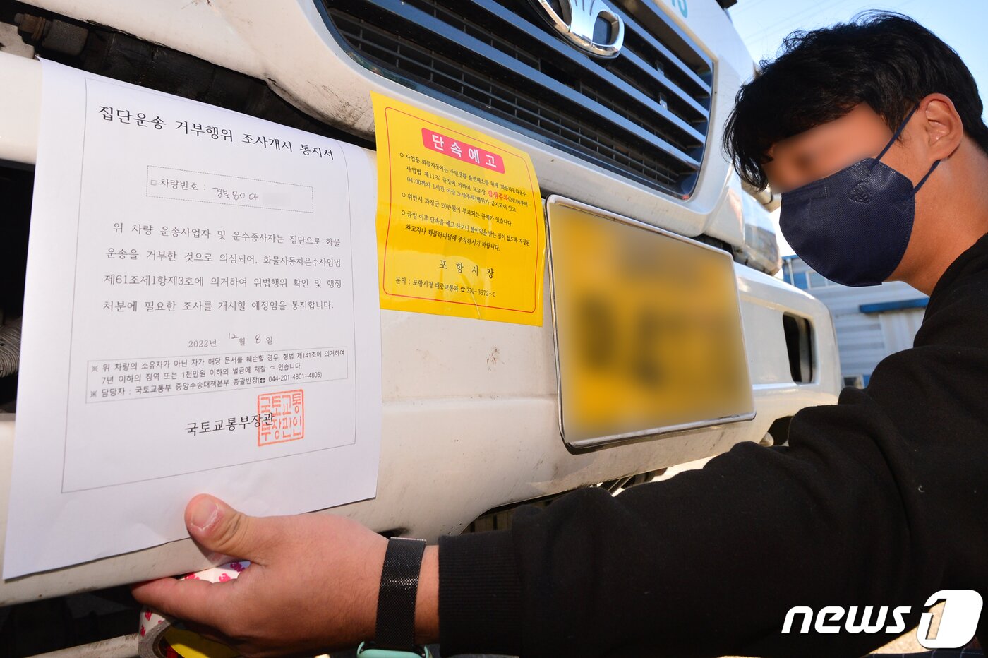 본문 이미지 - 8일 오후 정부가 화물연대 파업과 관련 시멘트에 이어 철강과 석유 화학 부문에 업무개시명령을 발동했다. 국토부 관계자가 경북 포항시 남구 철강공단에 멈춰서 있는 화물연대 포항지부 소속 화물차량에 업무개시명령서(집단운송 거부행위 조사개시 통지서)와 불법주차단속을 알리는 스티커를 부착하고 있다. 2022.12.8/뉴스1 ⓒ News1 최창호 기자