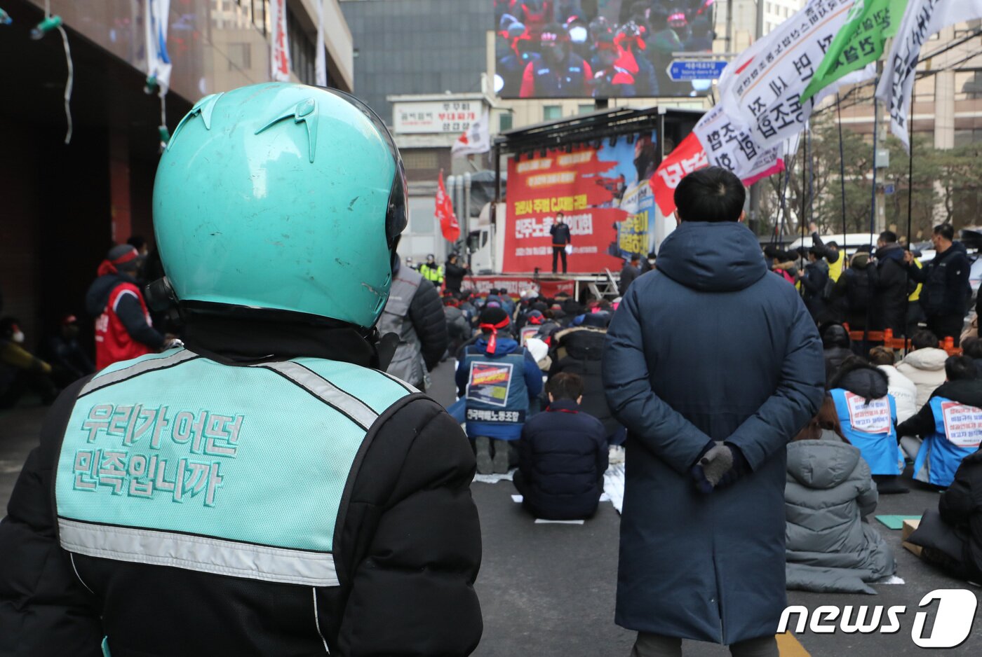 본문 이미지 - 한 배달원이 11일 서울 중구 CJ대한통운 앞에서 열린 '사회적 합의이행 거부! 택배대란 사태 주범! CJ대벌 규탄! 민주노총 결의대회'를 지켜보고 있다. 2022.2.11/뉴스1 ⓒ News1 이성철 기자