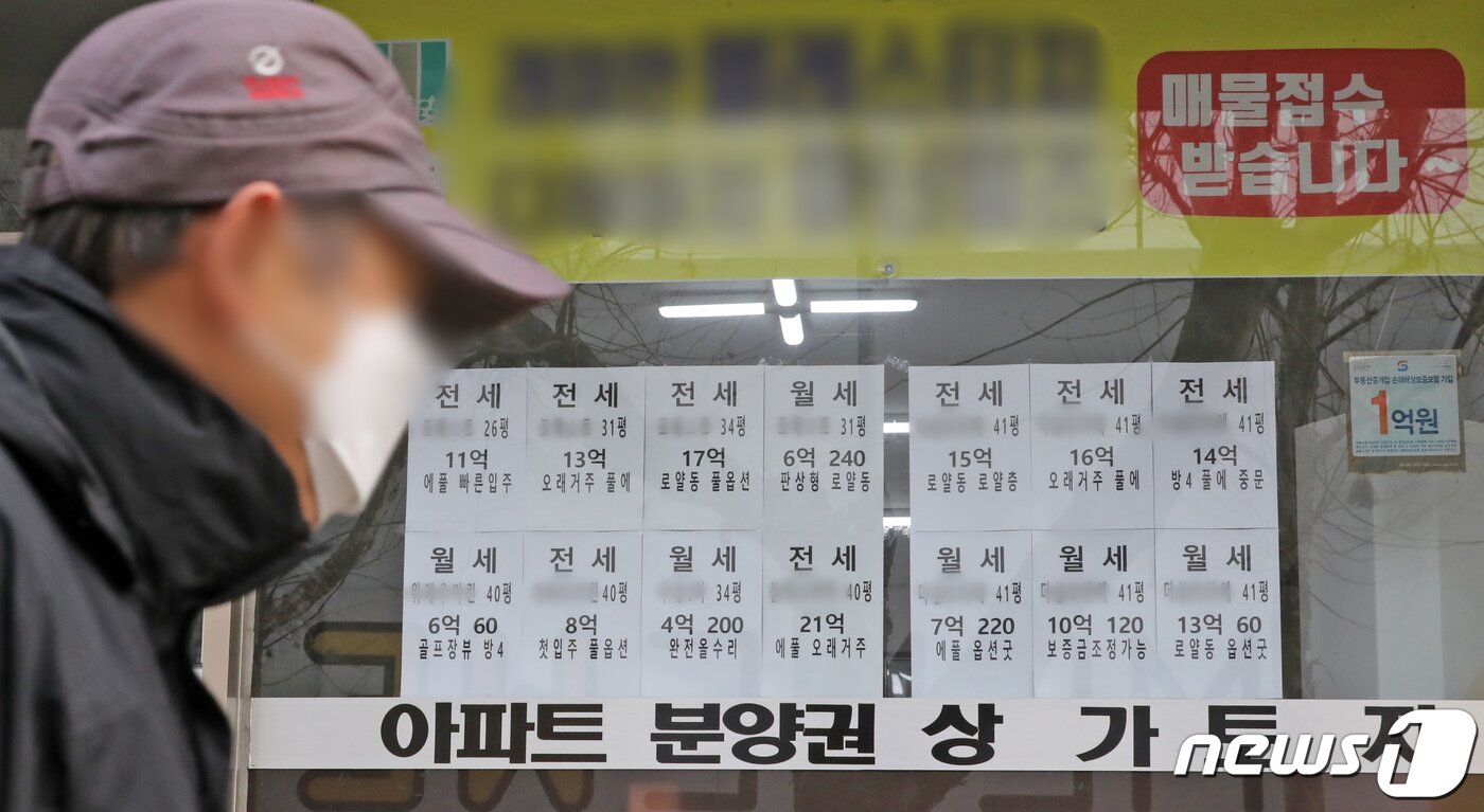 본문 이미지 - 한 부동산 공인중개사 사무소에 붙어진 매물 가격표 앞으로 시민이 지나가고 있다. 뉴스1 ⓒ News1 장수영 기자