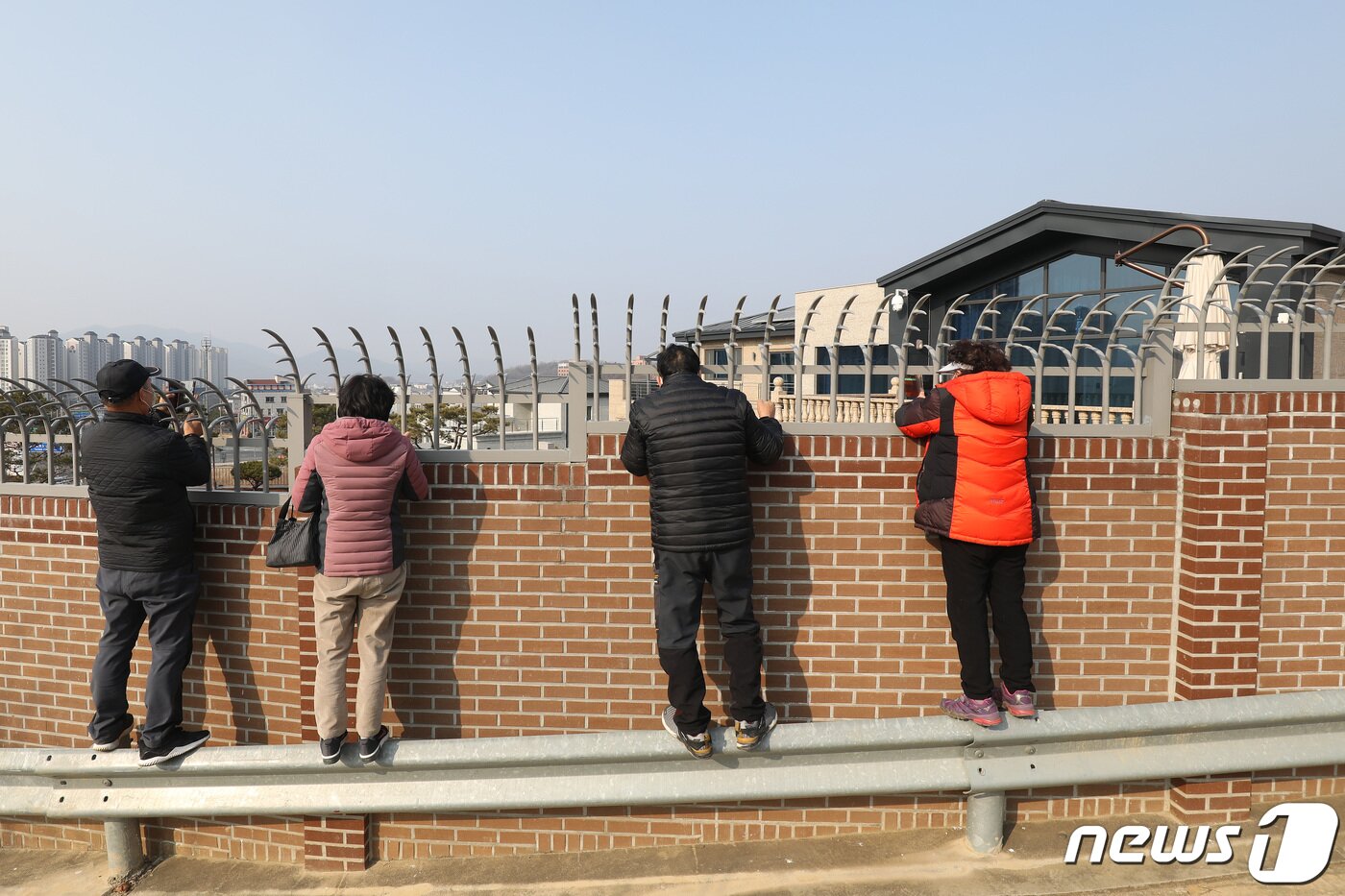 본문 이미지 - 박근혜 전 대통령이 퇴원 후 정치적 고향인 대구에서 생활하기 위해 달성군 유가읍 쌍계리의 한 주택을 본인 명의로 매입한 사실이 알려진 가운데 13일 사저를 구경하려는 시민들이 건물 뒤편 가드레일 위에 올라가 담장 안을 살펴보고 있다. 2022.2.13/뉴스1 ⓒ News1 공정식 기자