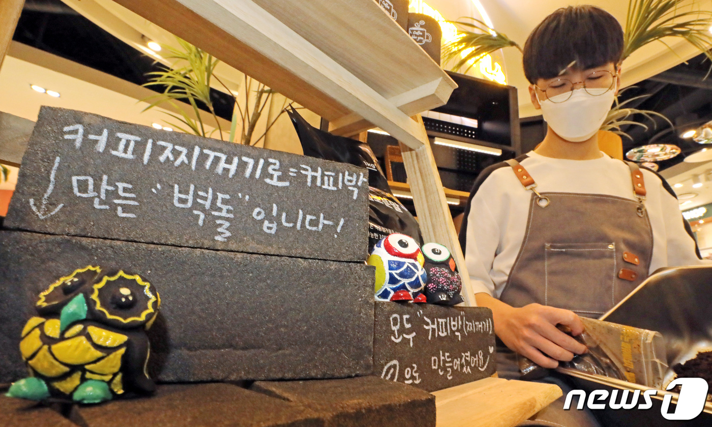 (서울=뉴스1) 장수영 기자 = 15일 서울시 마포구 현대백화점 신촌점에 위치한 커피박환전소에서 직원이 커피찌꺼기(커피박)를 재활용한 인테리어 소품 옆에서 커피찌꺼기를 모으고 있다 …