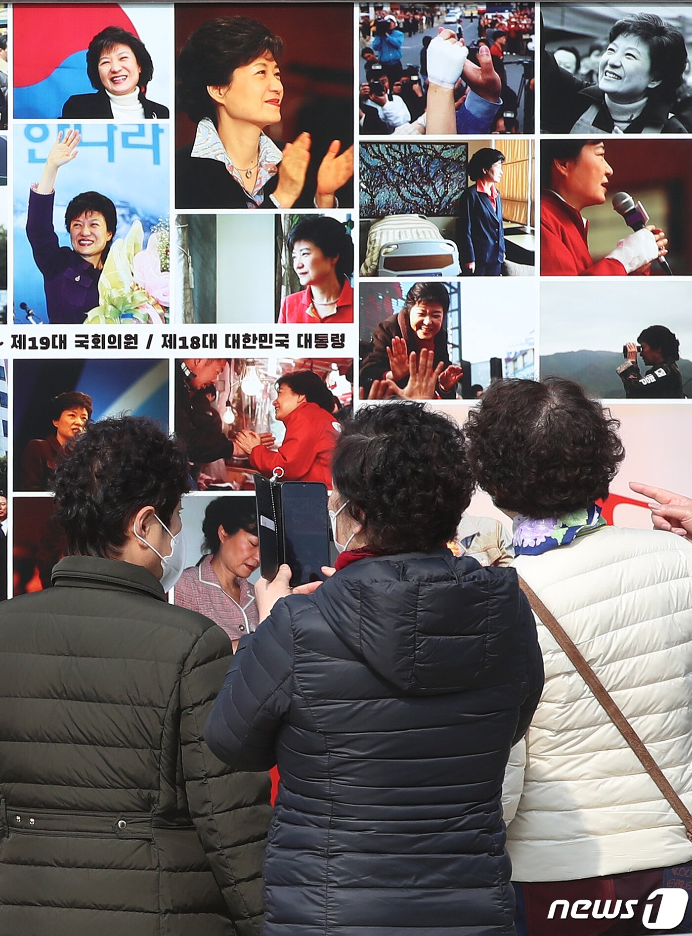 본문 이미지 - 박근혜 전 대통령 귀향과 입주를 하루 앞둔 23일 오후 지지자들이 사저 앞 게시대에 전시된 박 전 대통령 사진을 살펴보고 있다. 2022.3.23/뉴스1 ⓒ News1 공정식 기자