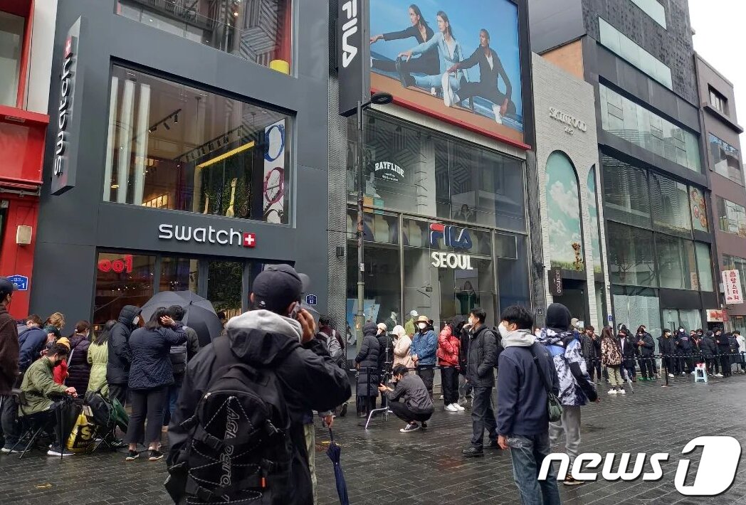 본문 이미지 - 26일 오전 서울 중구 스와치 명동점에서 시민들이 오메가와 스와치의 협업 시계 '문스와치(MoonSwatch)'를 사기 위해 길게 줄을 서 있다. 스와치는 명품 시계 브랜드 '오메가'와 협업해 30만원대의 시계 문스와치를 출시했다. 문스와치는 오메가를 상징하는 제품인 스피드마스터 문워치를 스와치식으로 재해석한 제품이다.(인스타그램 캡처)2022.3.27/뉴스1