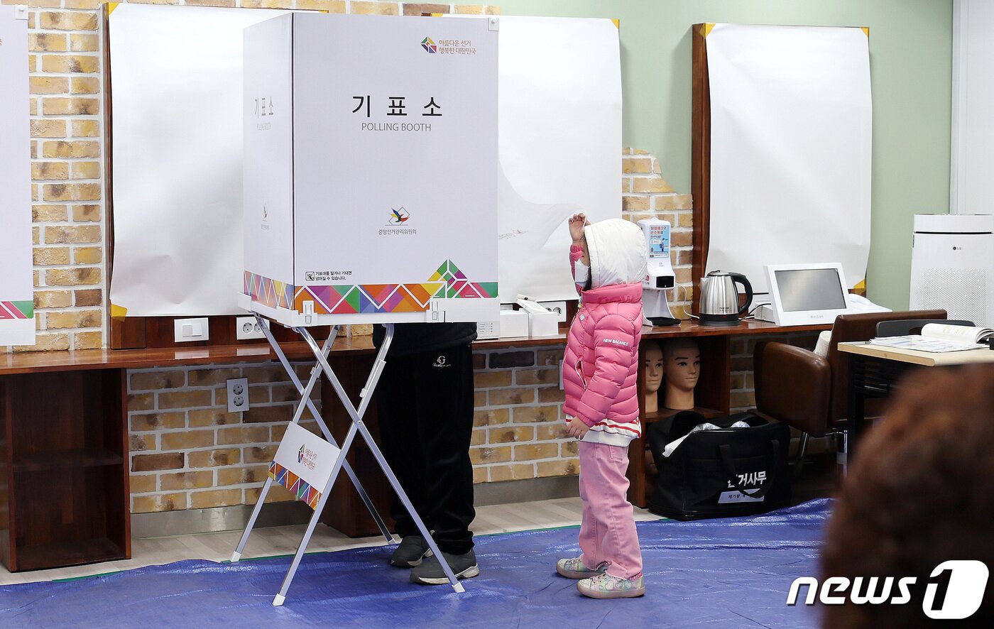 본문 이미지 - 제20대 대통령 선거일인 9일 서울 동대문구 정화여자상업고등학교 별관 헤어미용실습실에 마련된 투표소에서 어린이가 기표소 안 엄마를 궁금해 하고 있다. 2022.3.9/뉴스1 ⓒ News1 박지혜 기자