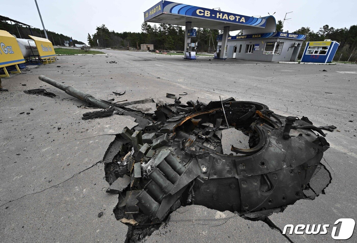 본문 이미지 - 12일(현지시간) 우크라이나 수도 키이우 인근에서 파괴된 러시아 군 탱크의 잔해와 주유소가 보인다. ⓒ AFP=뉴스1 ⓒ News1 우동명 기자