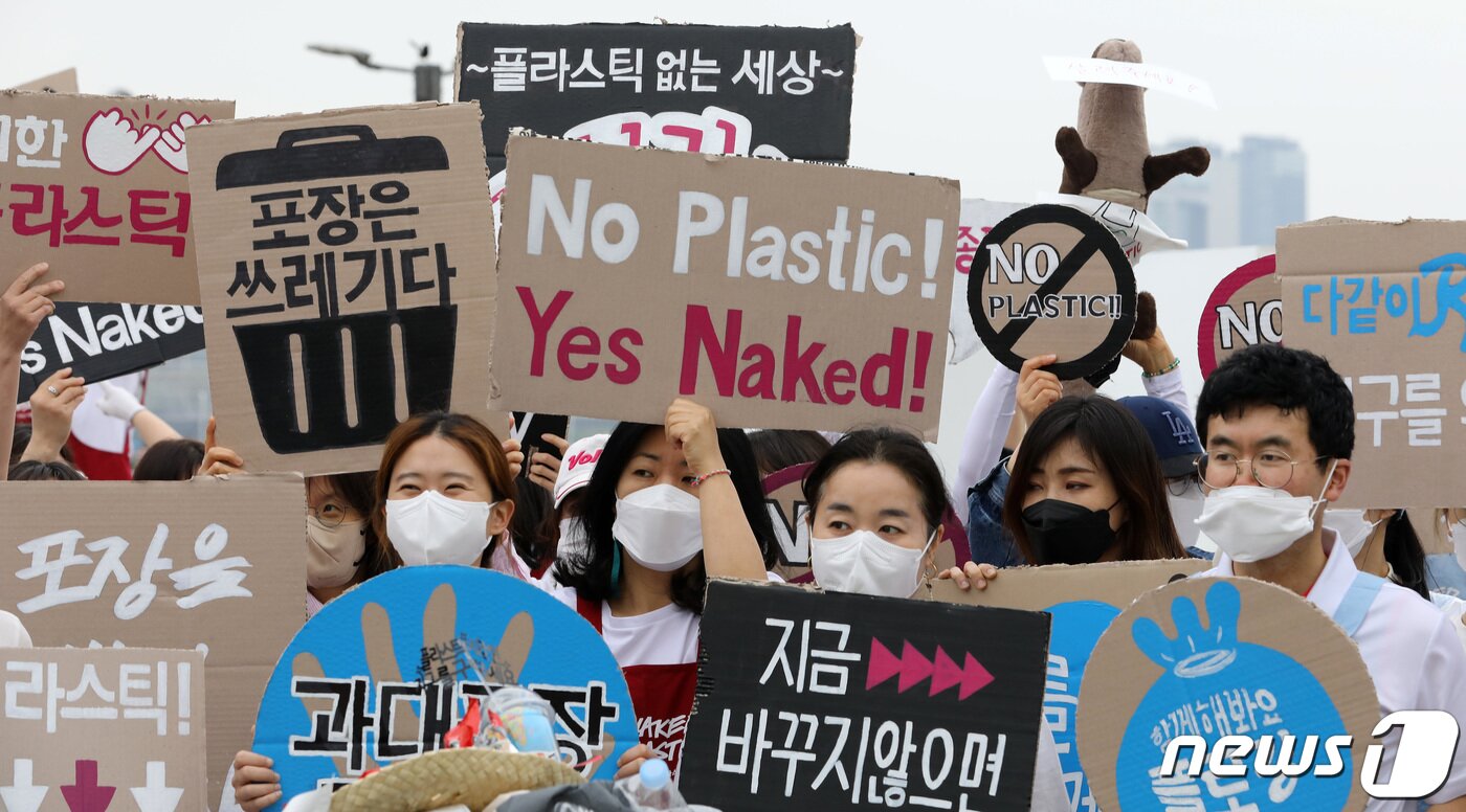 본문 이미지 - 시민활동가들이 22일 서울 영등포구 여의도 한강공원에서 지구의 날을 맞아 플라스틱 등 일회용 포장제 쓰레기를 줄이기 위한 '고 네이키드, 노 플라스틱' 캠페인에서 손 피켓을 들고 있다. 2022.4.22/뉴스1 ⓒ News1 이동해 기자