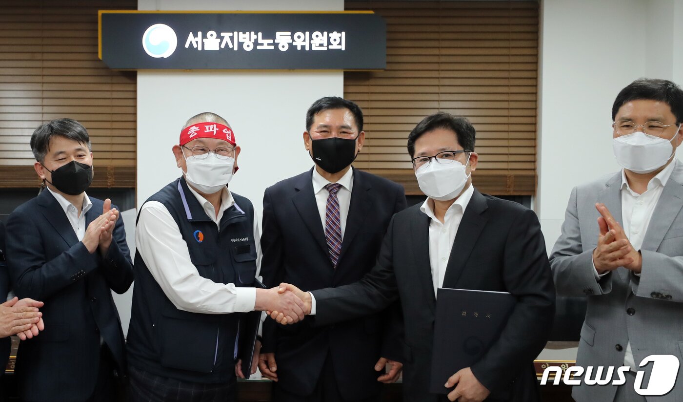 본문 이미지 - 조장우 서울시버스운송사업조합 이사장(오른쪽)과 박점곤 서울시버스노동조합 위원장이 26일 서울 영등포구 서울지방노동위원회에서 열린 조정회의사후조정에서 조정안에 서명한 뒤 악수를 하고 있다. 2022.4.26/뉴스1 ⓒ News1 장수영 기자
