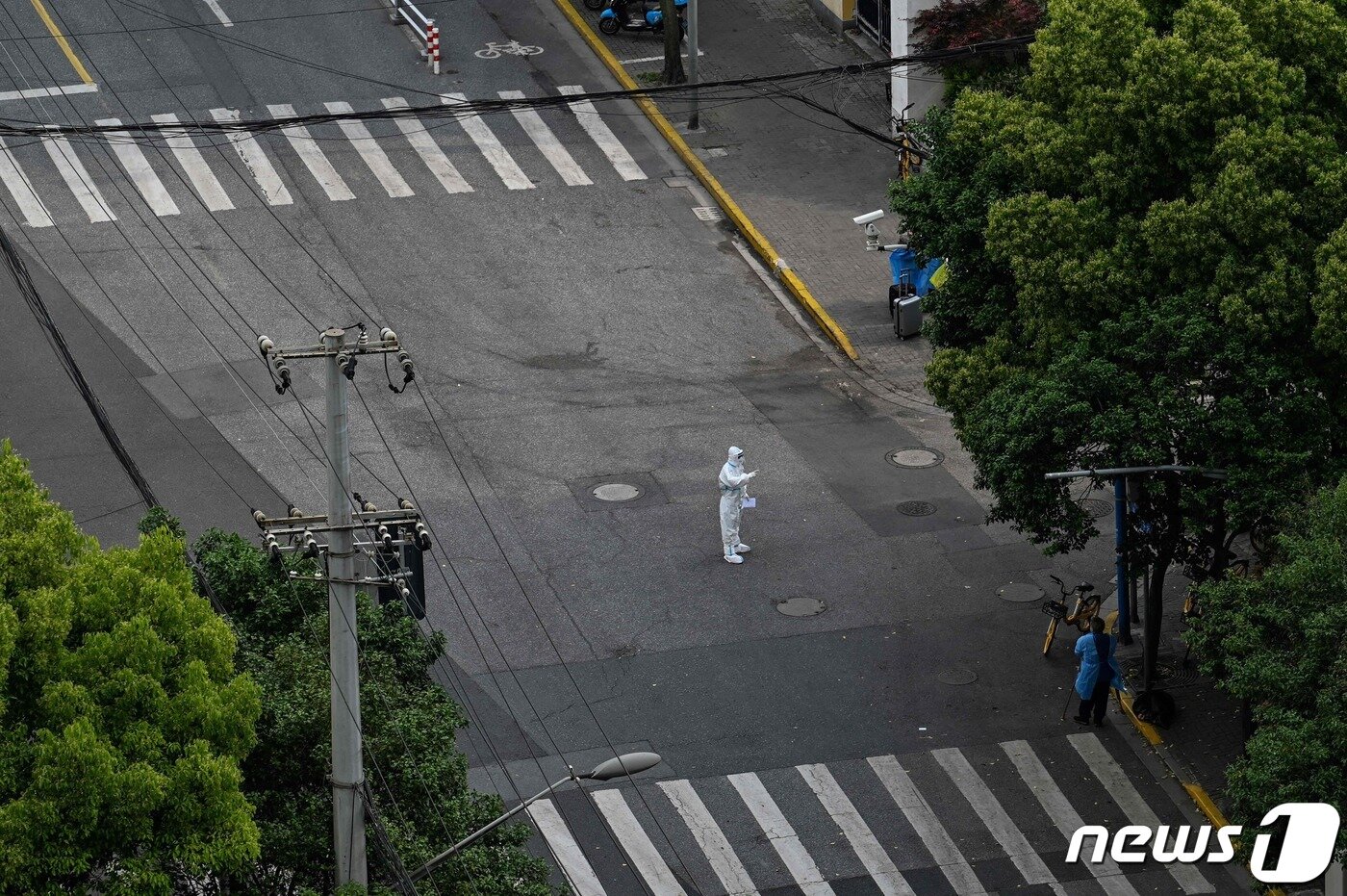 본문 이미지 - 25일 (현지시간) 코로나19 봉쇄 조치가 내려진 중국 상하이에서 방역요원이 텅 빈 거리서 순찰을 하고 있다. ⓒ AFP=뉴스1 ⓒ News1 우동명 기자