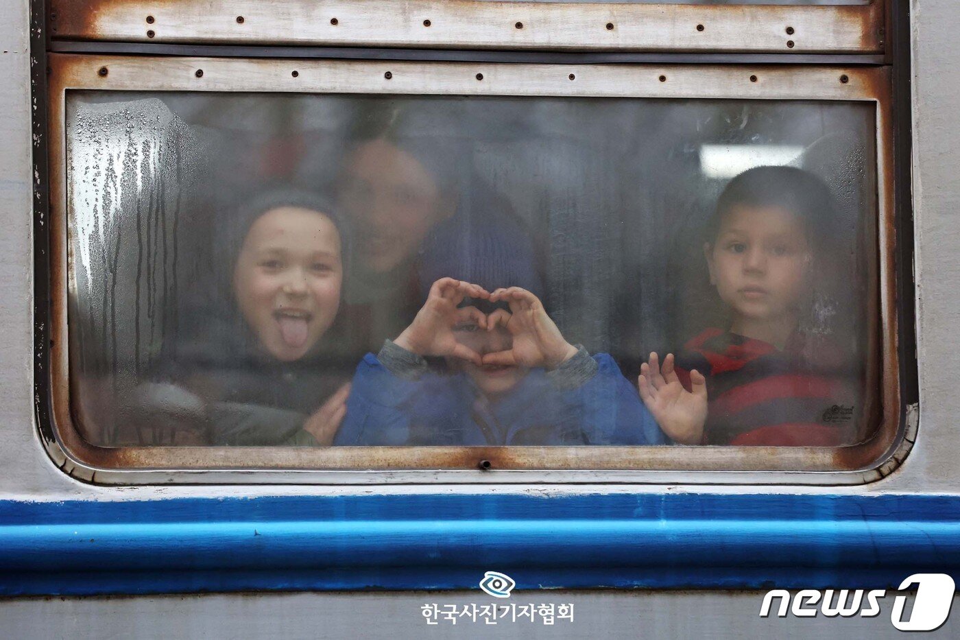 본문 이미지 - <이달의보도사진상 - 우수상> 러시아군이 우크라이나 수도인 키이우를 비롯해 하르키우, 마리우폴, 수미에서 민간인 대피를 위한 인도주의 통로를 개방키로 한 7일(현지시간) 키이우를 출발해 르비브를 지나 우크라이나 접경 도시인 폴란드 프셰미실 중앙역에 도착한 열차에서 피란민들이 창밖을 향해 하트를 만들어 보이고 있다. 2022.3.7 <조태형기자/ 뉴스1/ 한국사진기자협회 - 무단전재 재배포금지>