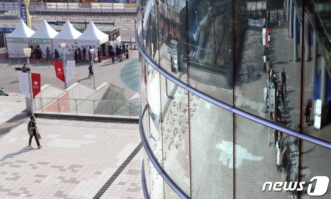 본문 이미지 - 4일 서울 중구 서울역에서 신종 코로나바이러스 감염증(코로나19) 검사를 받기 위해 임시선별진료소에 시민들이 줄을 서는 한편 대형마트 출입구에는 포켓몬빵을 구매하려 줄을 선 시민들이 유리창에 반사돼 보이고 있다. 2022.4.4/뉴스1 ⓒ News1 장수영 기자