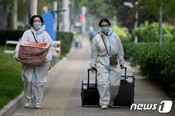 10일(현지시간) 코로나19 봉쇄령이 내려진 중국 베이징에서 방호복을 입은 주민이 가방과 짐을 가져 가고 있다. © AFP=뉴스1 © News1 우동명 기자