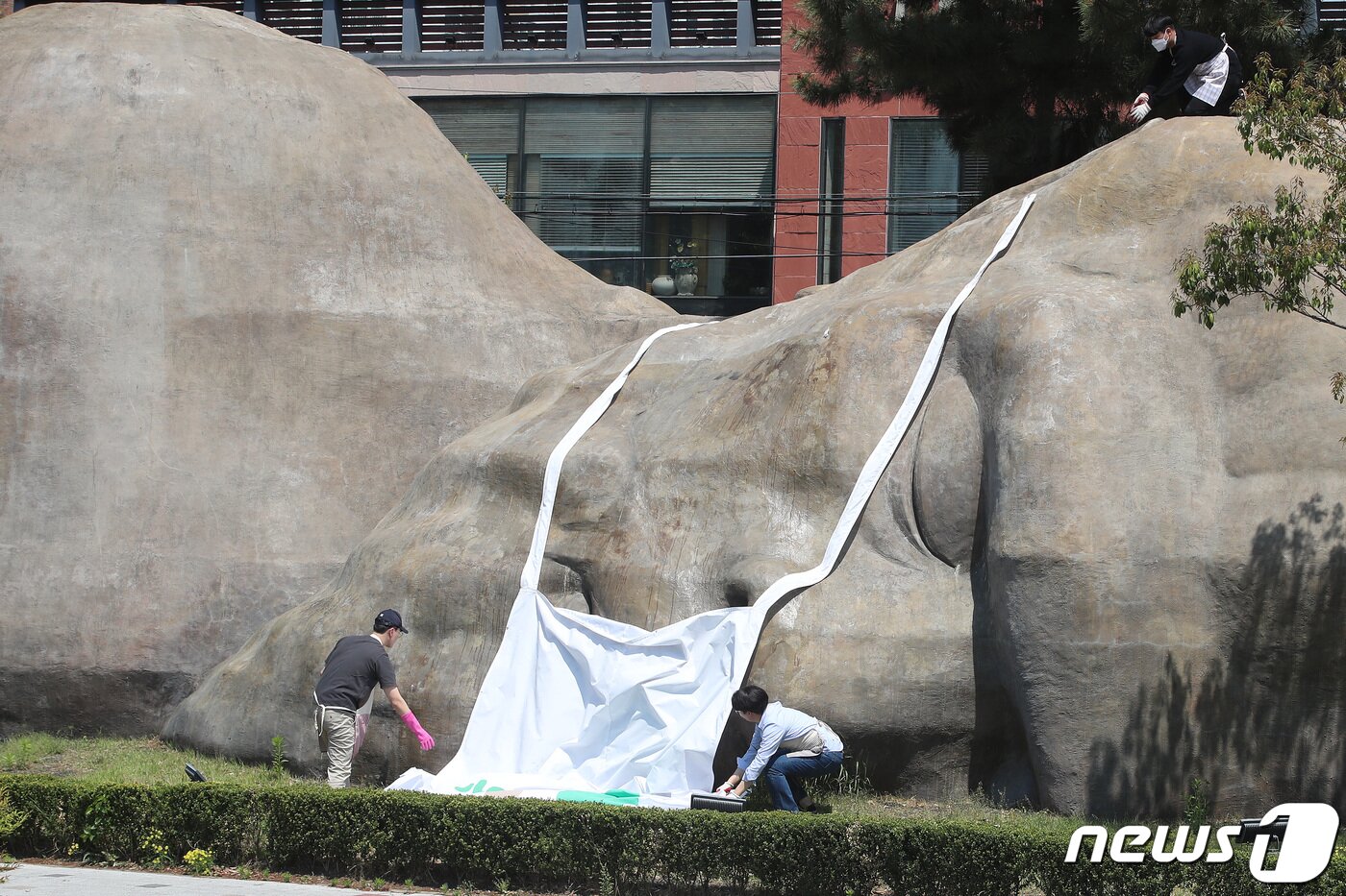 본문 이미지 - 실외 마스크 해제 첫날인 2일 오전 대구 달서구청 관계자들이 달서구 진천동 원시인 조형물에 씌워져 있던 마스크를 벗기고 있다.  2022.5.2/뉴스1 ⓒ News1 공정식 기자