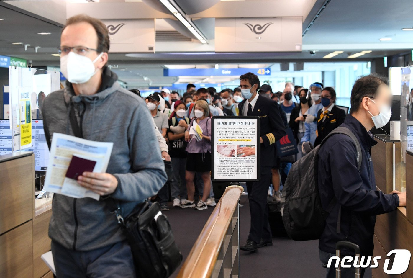 본문 이미지 - 27일 오전 인천국제공항 제1터미널 입국장에 해외 입국자들이 검역을 받기위해 대기하고 있다. 입국자들 앞에 원숭이두창 관련 안내문이 세워져 있다. &#40;공동취재&#41;2022.5.27/뉴스1 ⓒ News1 박세연 기자