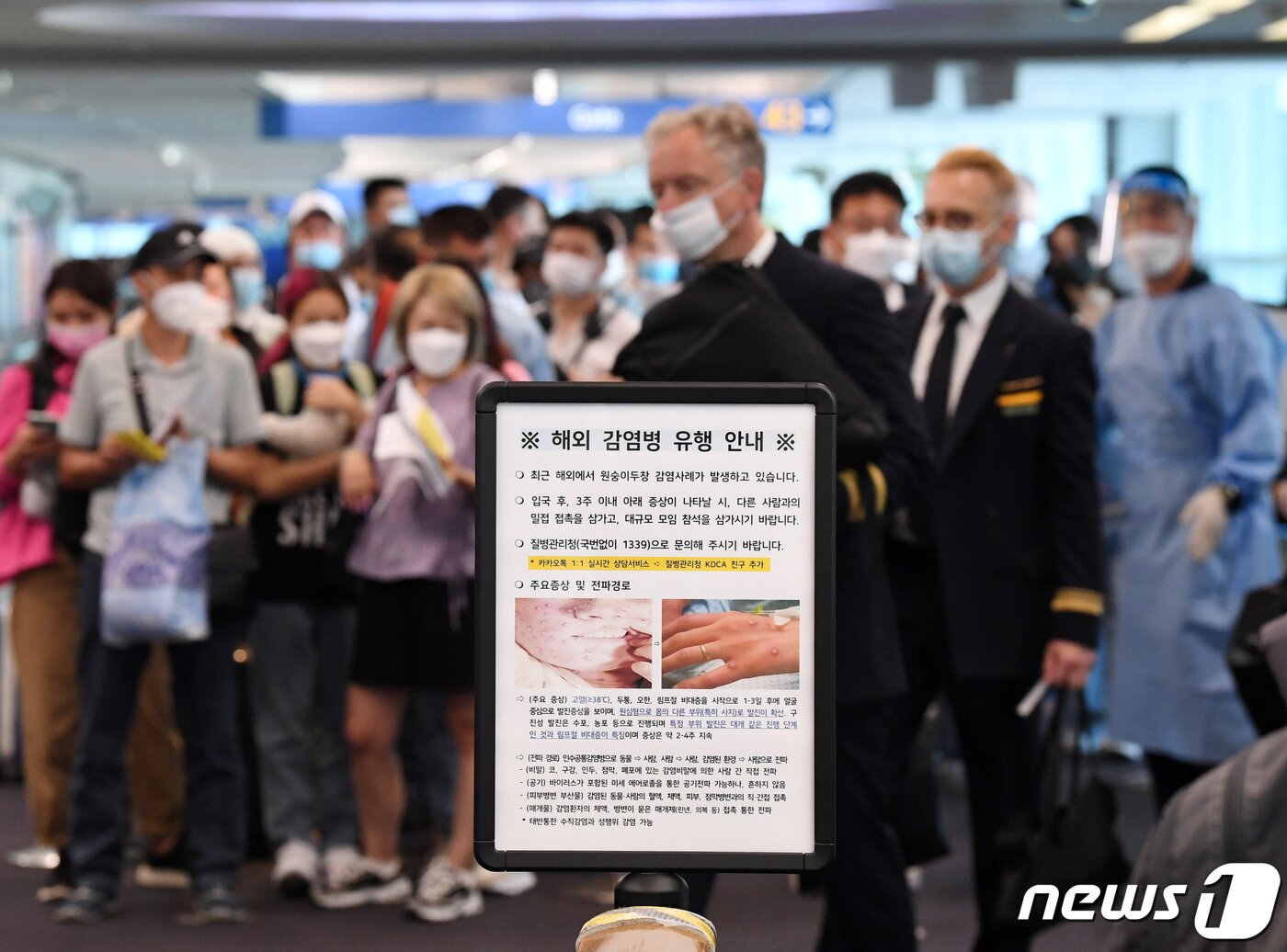 본문 이미지 - 27일 오전 인천국제공항 제1터미널 입국장에 해외 입국자들이 검역을 받기 위해 대기하고 있다. 입국자들 앞에 원숭이두창 관련 안내문이 세워져 있다. (공동취재)2022.5.27/뉴스1 ⓒ News1 박세연 기자
