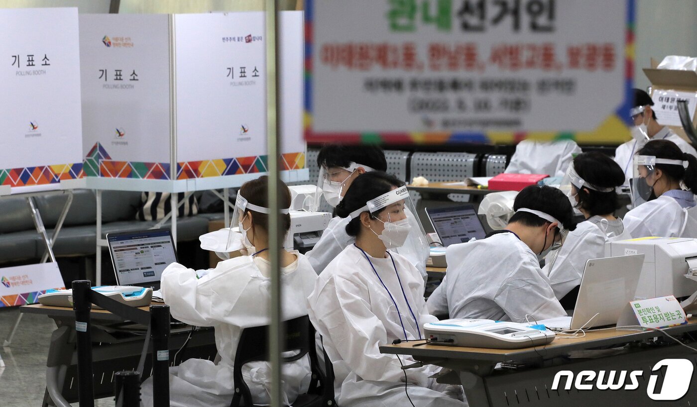 본문 이미지 - 제8회 전국동시지방선거 사전 투표 이틑날인 28일 오후 서울 용산구의회에 마련된 이태원 제1동 사전투표소에서 투표 참관인과 사무원들이 코로나19 확진자 투표를 앞두고 방호복을 착용하고 있다. 2022.5.28/뉴스1 ⓒ News1 구윤성 기자