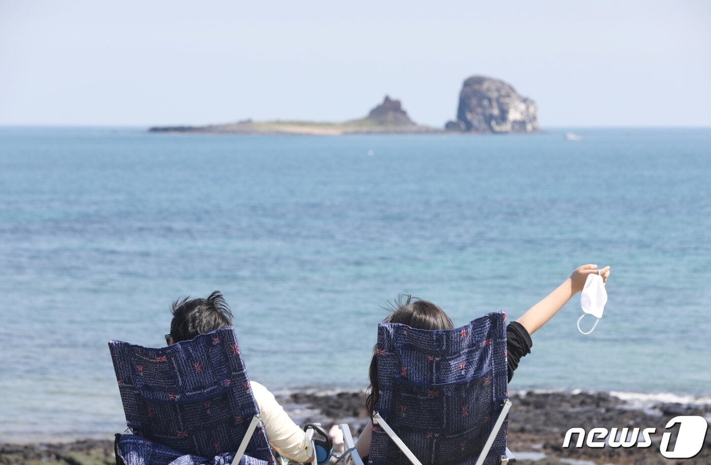 본문 이미지 - 실외 마스크 착용 의무 해제 둘째 날인 3일 오후 제주 서귀포시 안덕면 해안도로에서 여행객들이 간이 의자에 앉아 형제섬과 바다를 감상하고 있다.2022.5.3/뉴스1 ⓒ News1 