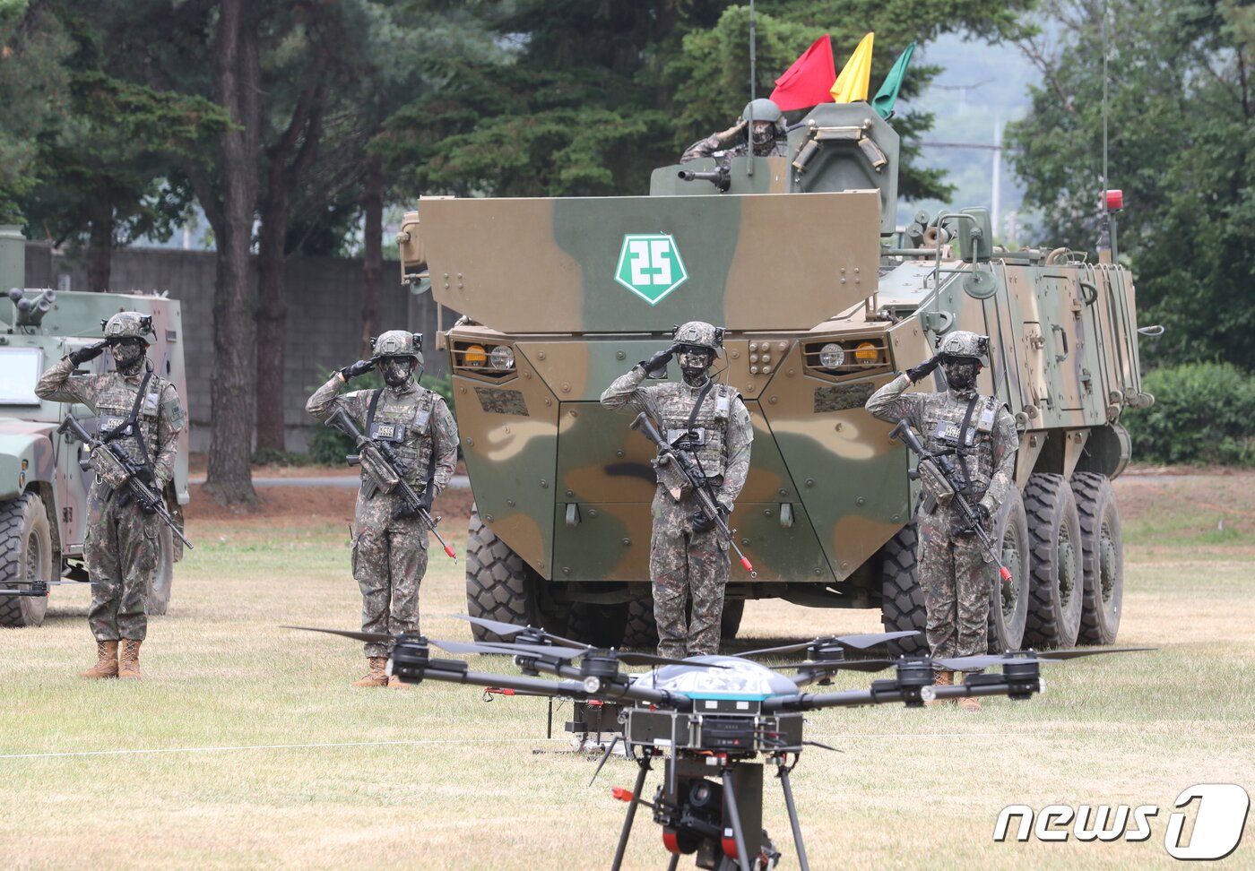 본문 이미지 - 10일 오전 경기도 양주시 25사단에서 열린 육군 '아미타이거 시범여단전투단 선포식 후' 유 무인 복합전투체계 전투 시연'에 동원된 드론을 배경으로 아미타이거 부대원들이 경례를 하고 있다.  2022.6.10/뉴스1 ⓒ News1 사진공동취재단