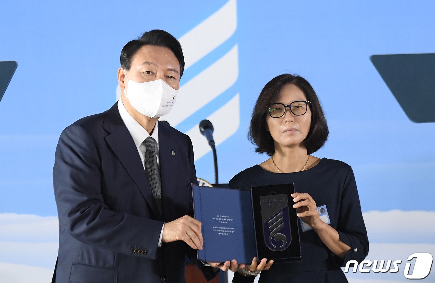 본문 이미지 - 윤석열 대통령이 17일 서울 용산구 전쟁기념관에서 열린 '국가유공자 및 보훈 가족 초청 오찬'에서 지난 2020년 의암호 수초섬 고정작업과 인명구조 중 순직한 고 이종우 경감 아내 손정희 씨에게 국가유공자 명패를 수여하고 있다. (대통령실사진기자단) 2022.6.17/뉴스1 ⓒ News1 안은나 기자