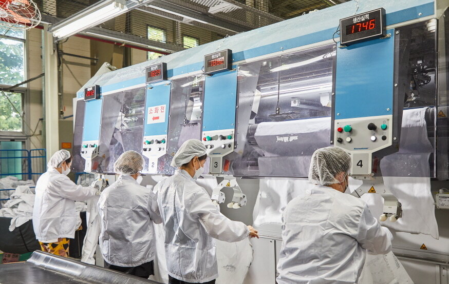 본문 이미지 - 크린토피아 의료세탁 공장에서 직원들이 아이러너에 천을 넣고 있다.(크린토피아 제공)ⓒ 뉴스1