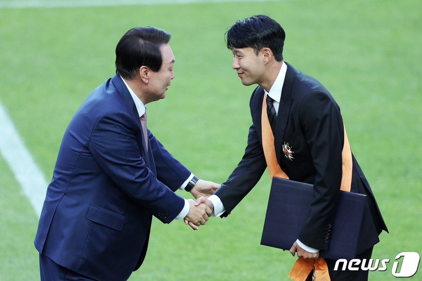 본문 이미지 - 윤석열 대통령이 2일 서울월드컵경기장에서 2002 한일월드컵 20주년 기념 평가전 대한민국-브라질의 경기에 앞서 잉글랜드 프로축구 프리미어리그(EPL)에서 아시아 선수 최초로 득점왕을 차지한 손흥민에게 체육훈장 최고등급인 청룡장을 수여한 뒤 악수를 나누고 있다. 2022.6.2/뉴스1 ⓒ News1 조태형 기자