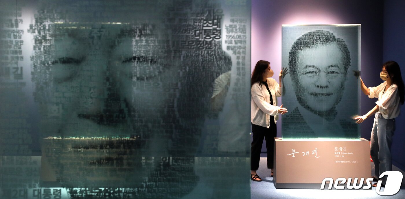 본문 이미지 - 문재인 전 대통령의 주요 기록물이 오는 21일 부터 세종시 대통령기록관에서 일반에 공개된다. 20일 오후 세종시 어진동 대통령 기록관에서 취임 연설문 핵심 단어를 이용해 대통령의 얼굴을 8장의 유리로 재현한 문자그림(텍스트아트) 조형물을 관계자들이 살펴보고 있다.2022.6.20/뉴스1 ⓒ News1 김기남 기자