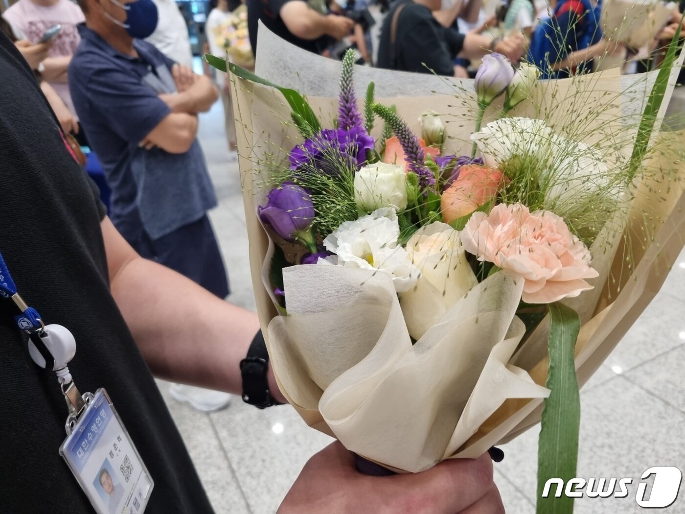 본문 이미지 - 대한수영연맹 직원들이 입국하는 수영 대표팀 32명 전원에게 줄 꽃다발을 들고 기다리고 있다.ⓒ 뉴스1