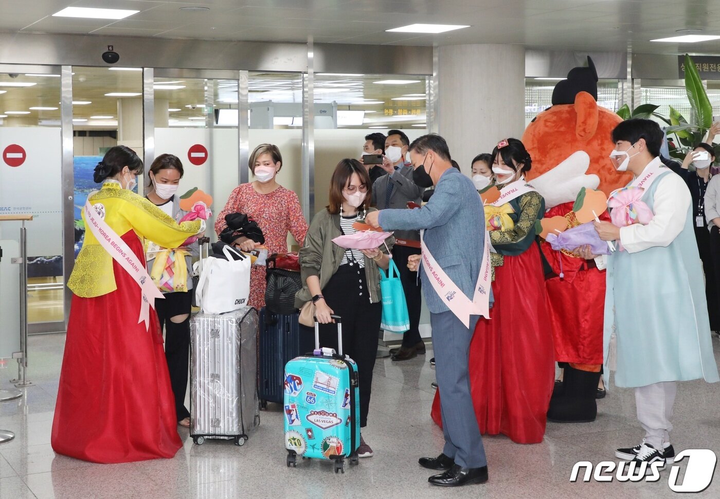 본문 이미지 - 3일 오전 제주국제공항 국제선 도착장에서 제주도와 제주관광공사 직원 등이 태국 관광객들에게 기념품을 나눠주고 있다. 지난 1일자로 제주 무사증(무비자) 일시 정지가 해제돼 2년여 만에 제주공항 국제선이 재개, 외국인 관광객이 인천공항을 거치지 않고 제주로 직접 입도할 수 있게 됐다. 2022.6.3/뉴스1 ⓒ News1 고동명 기자