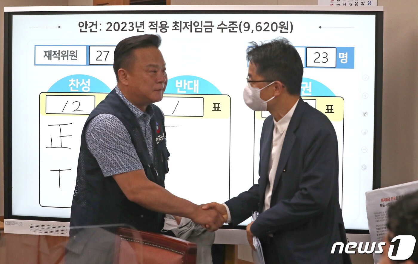 본문 이미지 - 30일 새벽 정부세종청사 최저임금위원회 회의실에서 열린 제8차 전원회의에서 재적 27, 출석 23, 찬성12, 반대1, 기권 10으로 2023년 최저임금이 9천620원으로 결정되며 박준식 최저임금위원회 위원장과 한국노총 이동호 사무총장이 악수를 나누고 있다. 2022.6.29/뉴스1 ⓒ News1 김기남 기자