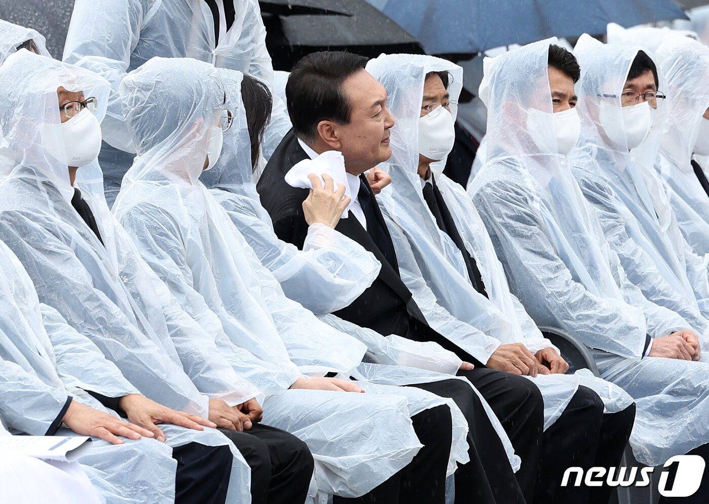 본문 이미지 - 윤석열 대통령 부인 김건희 여사가 6일 서울 동작구 국립서울현충원에서 열린 제67회 현충일 추념식에서 윤 대통령이 양복 자켓에 떨어진 빗물을 수건으로 닦아주고 있다. (대통령실사진기자단) 2022.6.6/뉴스1 ⓒ News1 오대일 기자