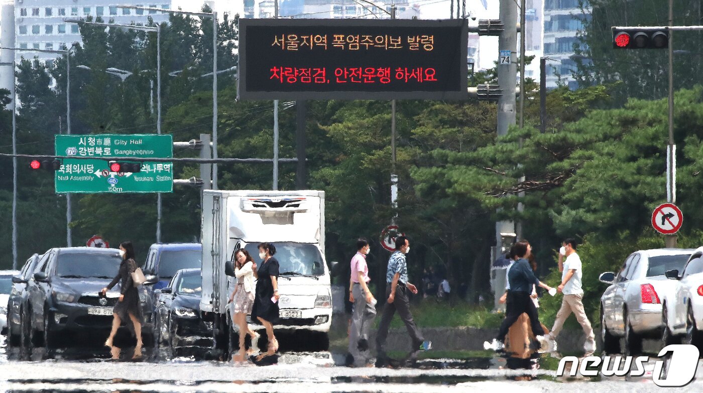 본문 이미지 - 삼복더위의 두 번째 '중복'인 26일 오후 서울 여의도공원 앞 횡단보도에 아지랑이가 피어오르고 있다. 동해안을 제외한 전국 대부분으로 '폭염특보'가 내려진 가운데 서울 낮 기온 33도, 대구는 34도까지 치솟으며 무더위가 계속될 전망이다. 2022.7.26/뉴스1 ⓒ News1 임세영 기자