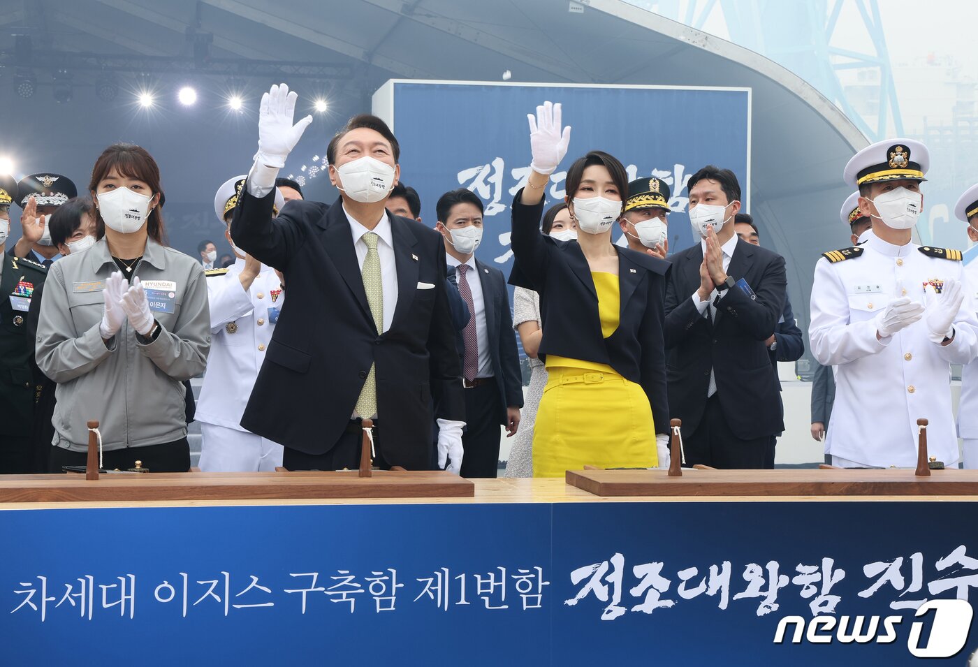 본문 이미지 - 윤석열 대통령과 부인 김건희 여사가 28일 울산 현대중공업에서 열린 정조대왕함 진수식에서 안전항해 기원 의식을 한 뒤 장병들을 향해 손을 흔들고 있다. 이 의식은 이음줄을 절단해 이와 연결된 샴페인이 선체에 부딪혀 깨짐으로써 액운을 막고 안전한 항해를 기원한다는 의미를 담고 있다. (대통령실사진기자단) 2022.7.28/뉴스1 ⓒ News1 안은나 기자