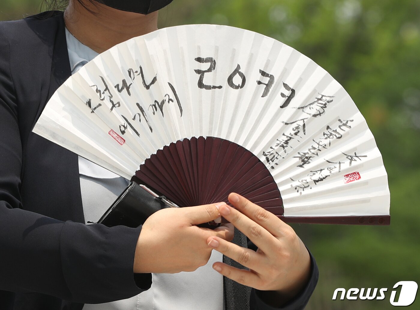 본문 이미지 - 김성진 아이카이스트 대표의 법률 대리인인 김소연 변호사가 5일 오후 경기 의왕시 서울구치소 앞에서 취재진을 향해 부채를 들어보이고 있다. 이준석 국민의힘 대표가 성상납을 받았다는 의혹을 수사 중인 서울경찰청 반부패·공공범죄수사대는 이날 오후 이 대표에게 접대를 제공했다고 주장하는 김 대표에 대한 2차 참고인 조사를 벌인다. 이와 관련해 국민의힘 중앙윤리위원회는 오는 7일 '성 상납 증거인멸교사 의혹' 징계 심의 결과를 발표할 예정이다. 2022.7.5/뉴스1 ⓒ News1 신웅수 기자
