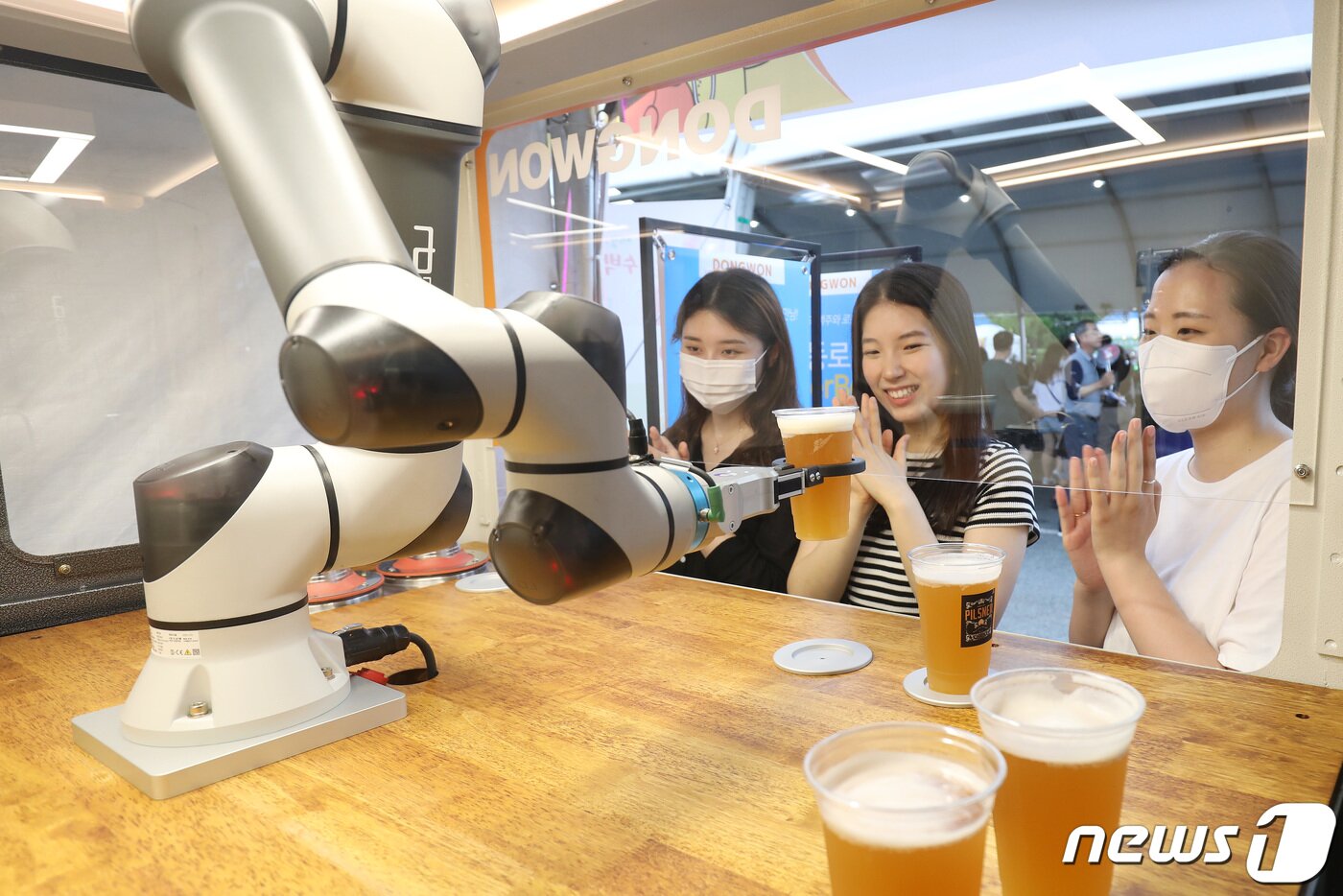 본문 이미지 - 6일 오후 대구 달서구 두류야구장에서 열린 '2022 대구치맥페스티벌'을 찾은 시민들이 로봇이 따라주는 맥주를 신기한 듯 바라보고 있다. 2022.7.6/뉴스1 ⓒ News1 공정식 기자