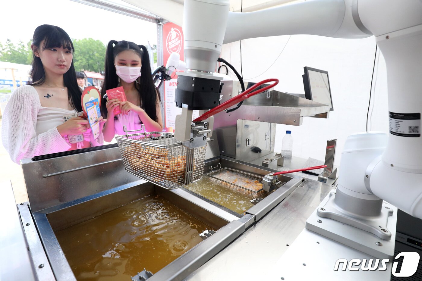 본문 이미지 - 6일 오후 대구 달서구 두류야구장에서 열린 '2022 대구치맥페스티벌'을 찾은 시민들이 치킨 튀겨주는 로봇을 신기한 듯 바라보고 있다. 2022.7.6/뉴스1 ⓒ News1 공정식 기자