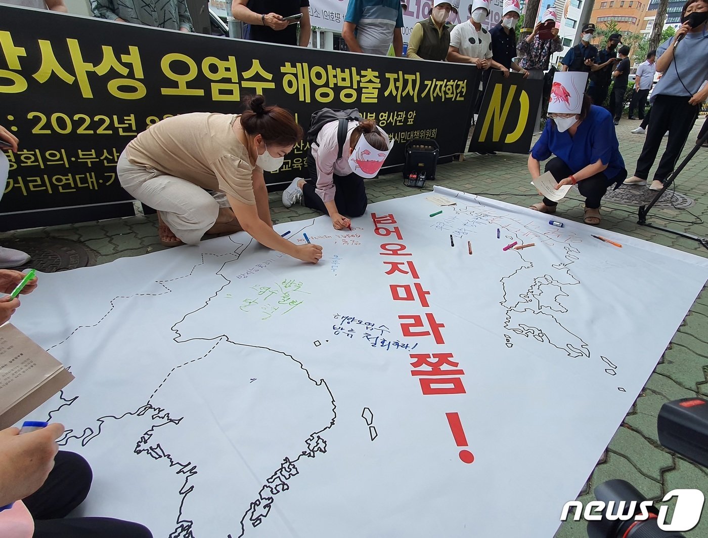 부산환경회의 등 부산지역 7개 환경단체 및 소비자단체가 10일 부산 동구 일본영사관 앞에서 열린 &#39;일본 후쿠시마 방사성 오염수 해양방출 저지를 위한 기자회견&#39; 중 퍼포먼스로 한반도와 일본 열도 사이 원전 오염수를 차단해야 한다는 문구가 새겨진 그림에 &#39;오염수 방류 철회&#39;를 글씨를 적고 있다.2022.8.10/뉴스1 노경민 기자 ⓒ News1