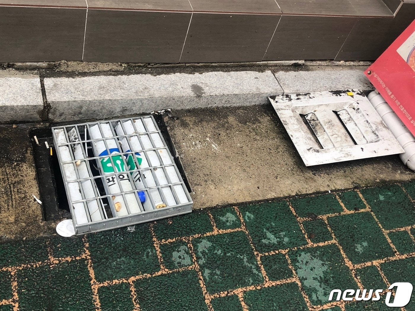 본문 이미지 - 13일 서울 관악구 신림동 한 PC방 앞에 설치된 빗물받이 덮개가 열려있다. 관악구 빗물받이엔 철망 사이엔 플라스틱 덮개가 추가 설치됐는데 이 틈 사이로 담배꽁초 등이 쌓여서 배수를 막고 있다. 8일 폭우가 내리던 날 배수가 되지 않자 주민이 덮개를 완전히 열었다.  22.08.13/ 뉴스1 ⓒ 뉴스1 한병찬 기자