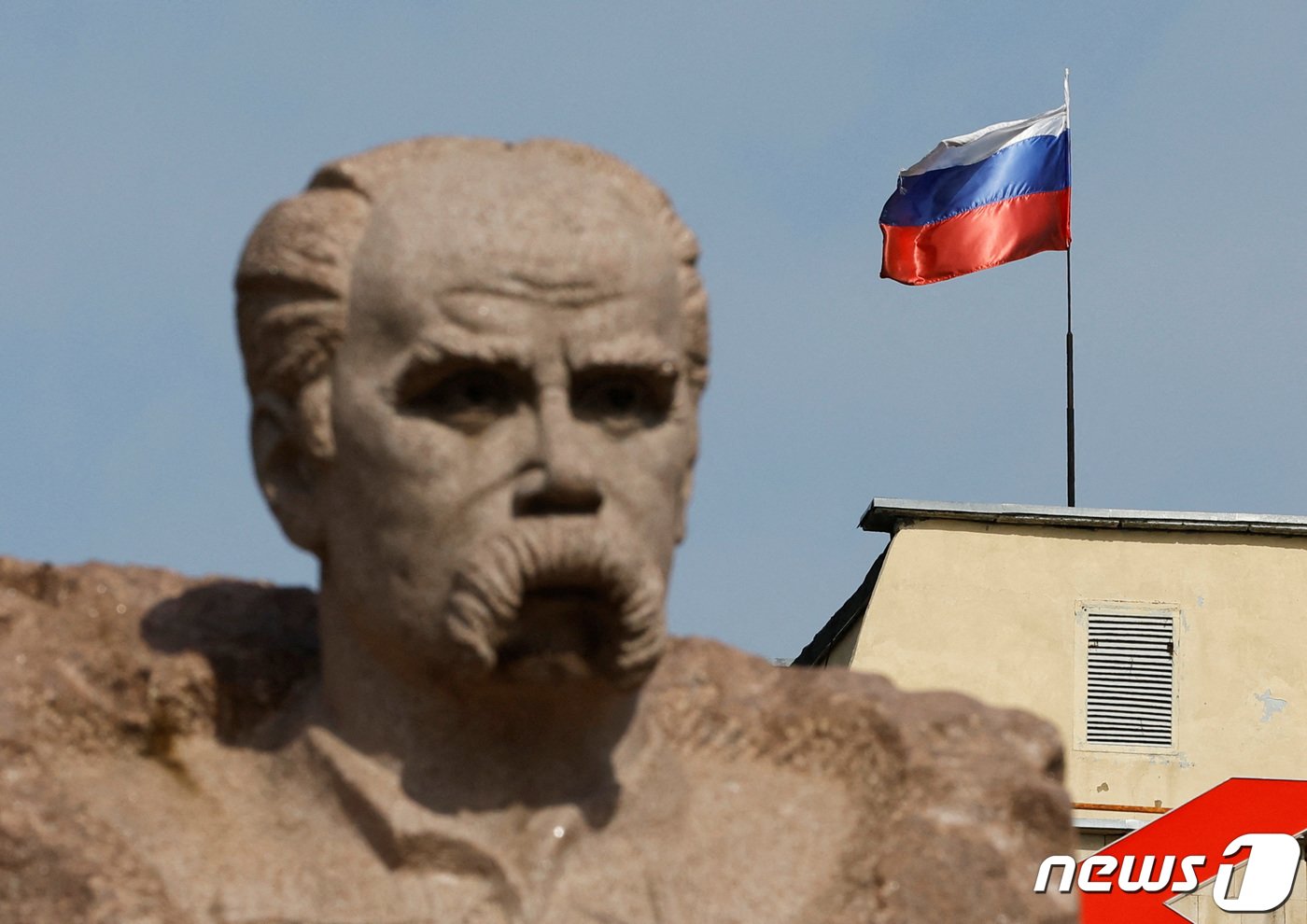 본문 이미지 - 우크라이나 자포리자 에네르호다르에 위치한 민족시인 타라스 쉐브첸코 석상 뒤로 러시아군이 점령 중인 자포리자 원자력 발전소 건물 꼭대기에 러시아 국기가 나부끼는 모습. 2022. 8. 23. ⓒ 로이터=뉴스1 ⓒ News1 최서윤 기자