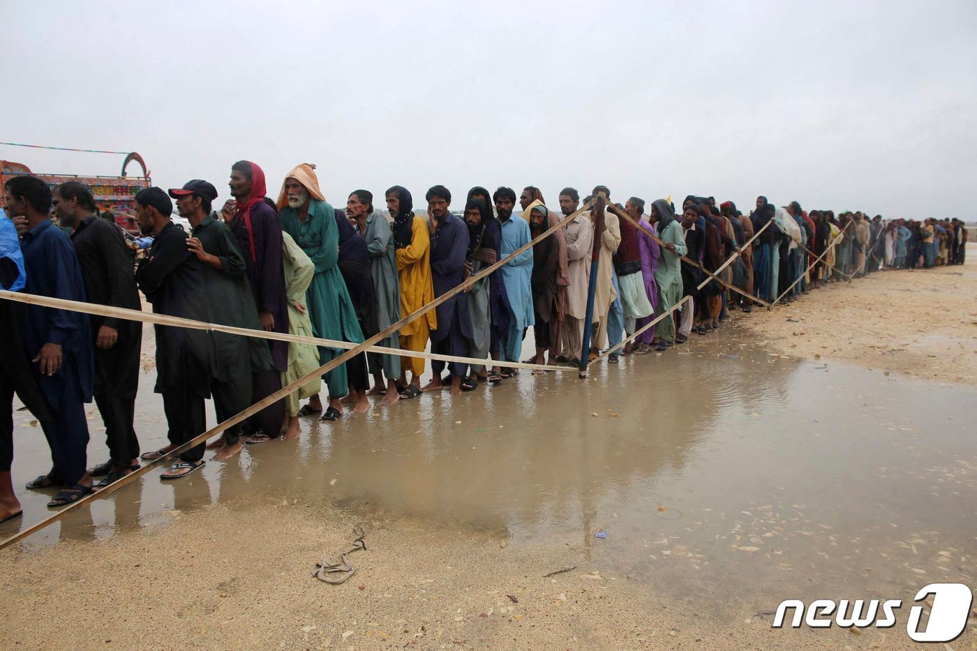 본문 이미지 - 24일 (현지시간) 물 폭탄이 쏟아진 파키스탄 하이데라바드에서 수재민들이 군에서 배급하는 음식을 받기 위해 길게 줄을 서 있다. ⓒ AFP=뉴스1 ⓒ News1 우동명 기자