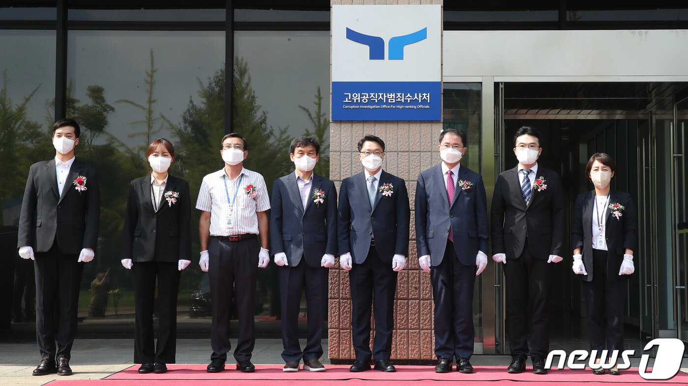 본문 이미지 - 김진욱 고위공직자범죄수사처(공수처) 처장과 참석자들이 26일 오전 경기도 과천시 공수처 앞에서 새로운 로고(CI)와 슬로건(표어)을 사용하는 현판 제막식을 갖고 있다. 왼쪽부터 여승현 운전실무관, 고솔잎 방호원, 황홍근 미화팀장, 김상춘 과천청사관리소장, 김진욱 처장, 여운국 차장, 차정현 검사, 이미라 행정직 직원. 2022.8.26/뉴스1 ⓒ News1 임세영 기자