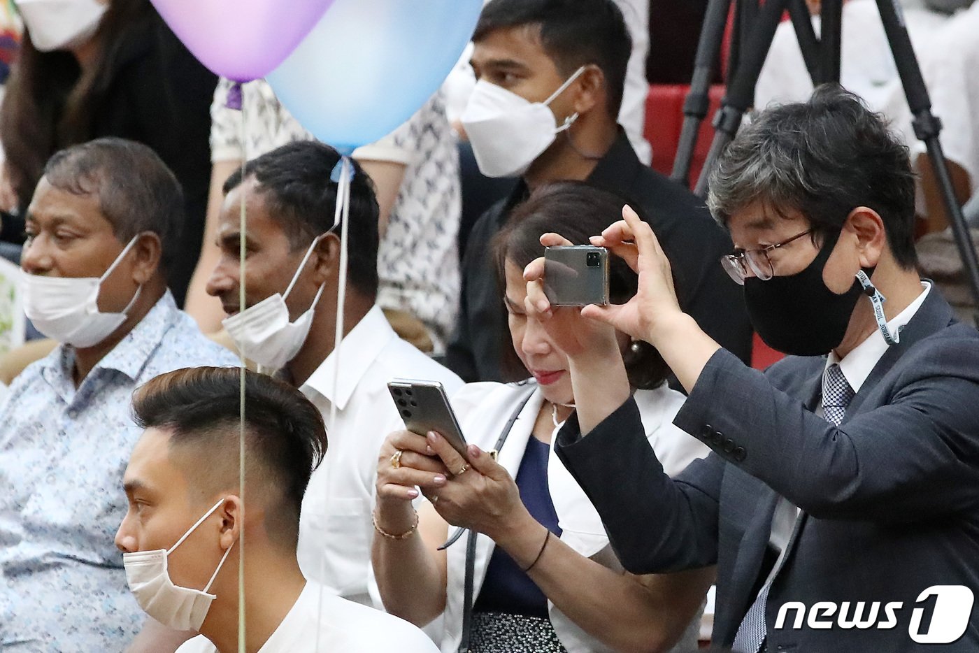 본문 이미지 -  고경수 목사(오른쪽)가 11일 오후 대구 달서구 신당동 계명문화대학교 체육관에서 열린 '2022년 이주민과 함께하는 추석 축제'에서 공연을 지켜보던 중 휴대전화를 꺼내 사진을 찍고 있다. 2022.9.12/뉴스1 ⓒ News1 공정식 기자