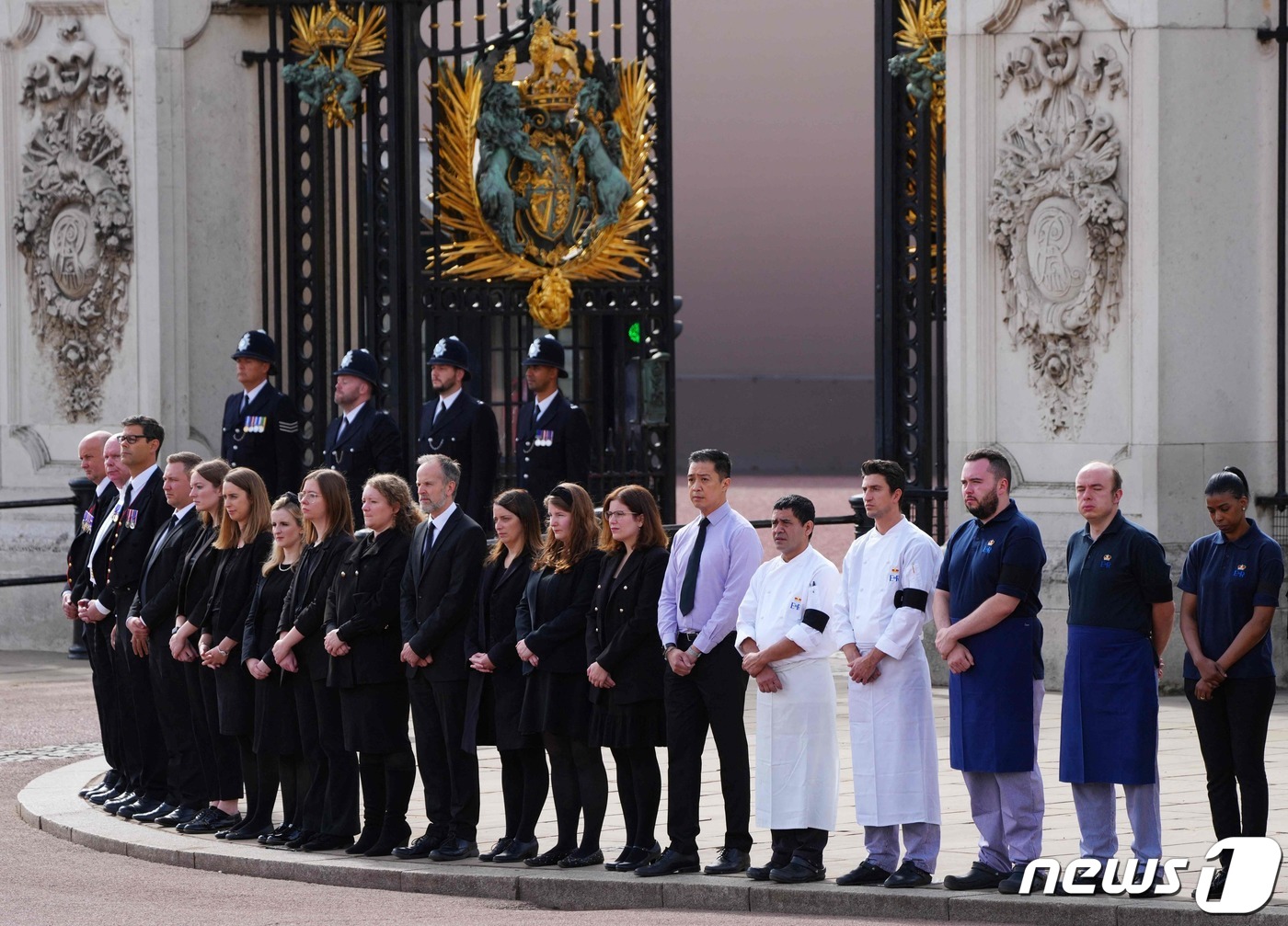 (AFP=뉴스1) = 19일(현지시간) 영국 런던 버킹엄 궁전 앞에서 궁전 직원들이 엘리자베스 2세 여왕의 국장이 엄수되는 동안 조의를 표하고 있다.ⓒ AFP=뉴스1