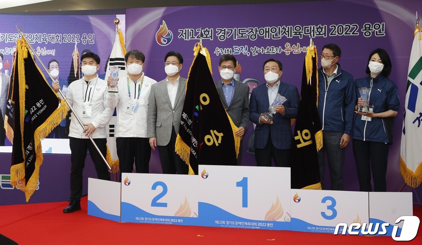 본문 이미지 - 경기도장애인체육대회 폐막식에서 종합 1위를 한 수원시와, 2위 성남시, 3위 부천시 관계자가 시상대에서 기념촬영을 하고 있다.(용인시 제공)