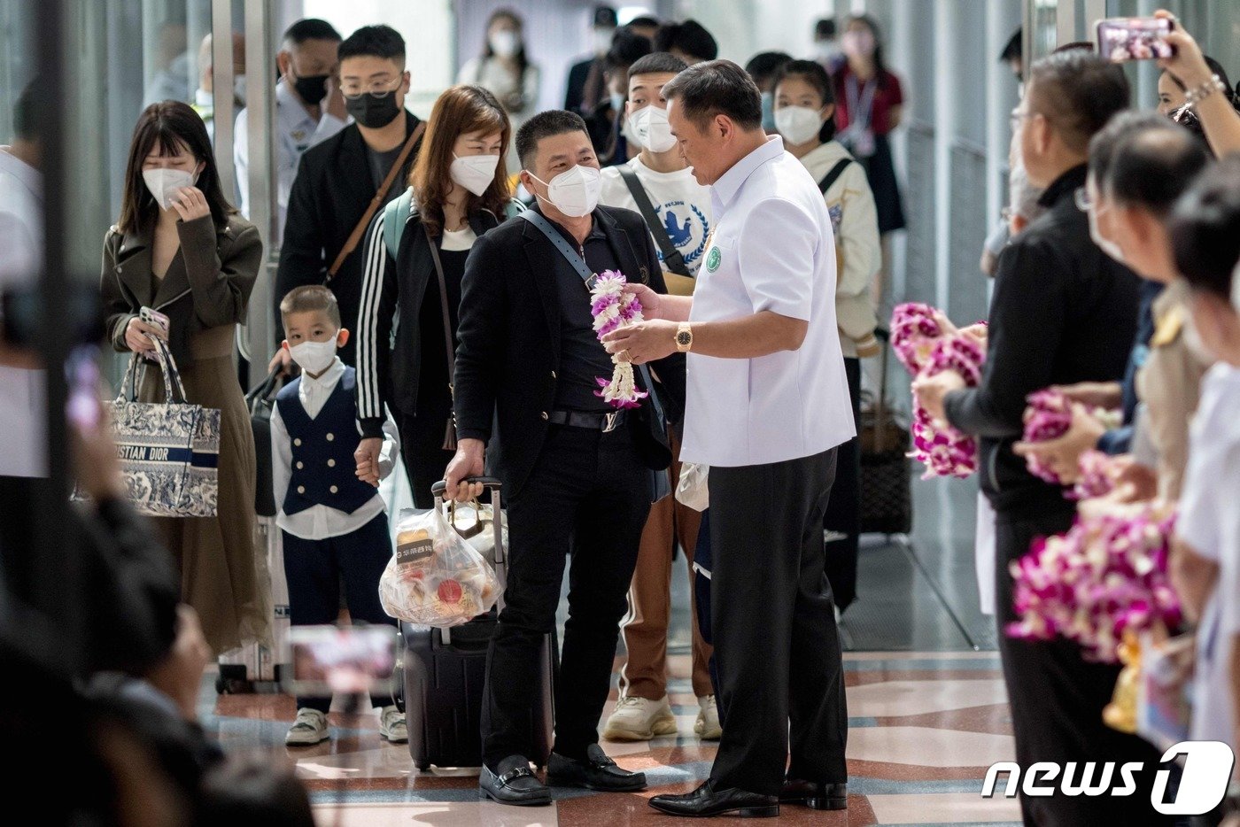 본문 이미지 - 아누틴 차른비라쿨 태국 보건부 장관이 9일&#40;현지시간&#41; 태국 방콕 수완나품 공항에서 중국 당국이 코로나19 여행 제한 조치를 철회한 이후 처음으로 입국한 중국인 관광객들에게 꽃을 선물해주고 있다. 2023.1.9. ⓒ AFP=뉴스1 ⓒ News1 김성식 기자