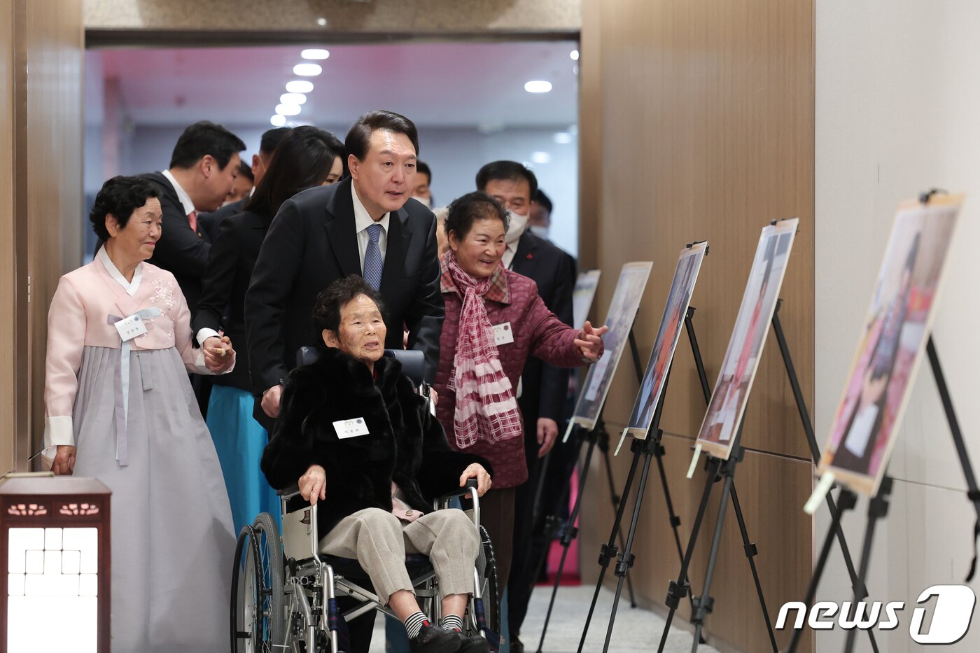 본문 이미지 - 윤석열 대통령이 12일 오후 용산 대통령실에서 칠곡할매글꼴의 주인공 이종희(91) 할머니의 휠체어를 끌며 할머니들의 사진을 보고 있다. 칠곡할매글꼴은 경북 칠곡군이 어르신 대상으로 운영하는 성인문예교실에서 한글을 깨친 할머니들의 글씨체로 윤 대통령 부부는 새해 연하장을 할머니의 서체로 제작했다. (대통령실 제공) 2023.1.12/뉴스1 ⓒ News1 안은나 기자