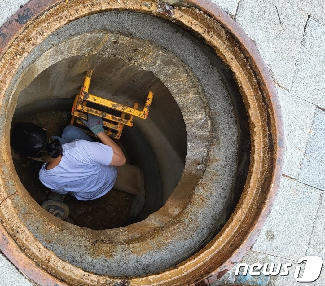 본문 이미지 -  2022년 여름 경기 남양주시 소속 수도검침원이 계량기 확인을 위해 맨홀 안으로 들어가고 있다. /뉴스1 양희문 기자
