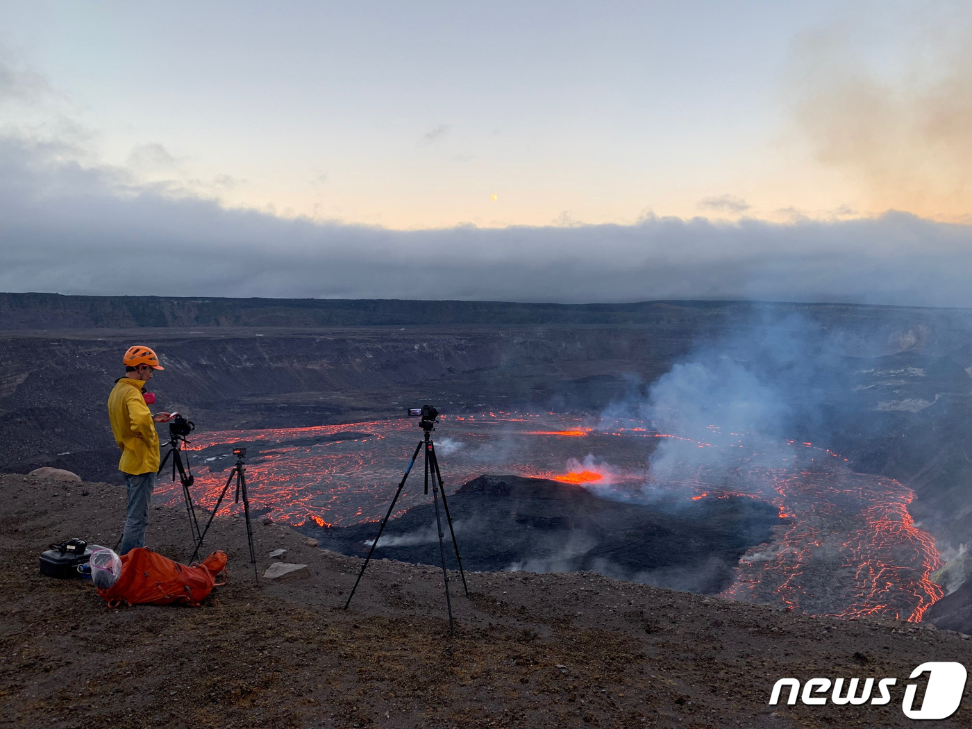 (하와이 로이터=뉴스1) 우동명 기자 = 5일(현지시간) 하와이에 있는 킬라우에아산 화산이 분화를 시작해 붉은 용암을 분출하는 모습을 지질학자가 촬영하고 있다.ⓒ 로이터=뉴스1