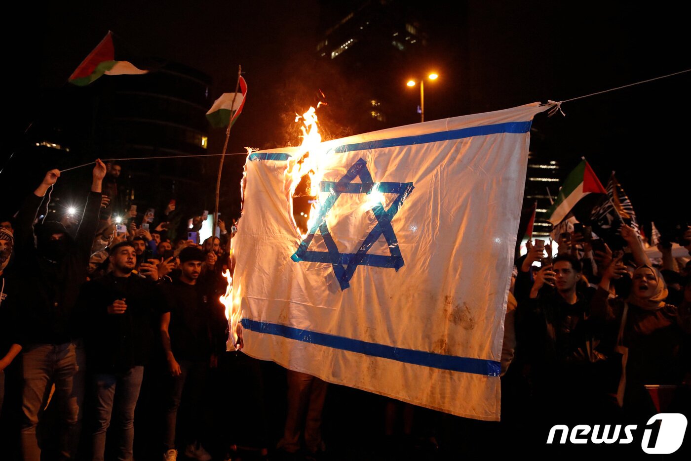 본문 이미지 - 시위대가 이스라엘 국기를 불태우고 있다. 2023.10.18 ⓒ 로이터=뉴스1 ⓒ News1 정지윤 기자
