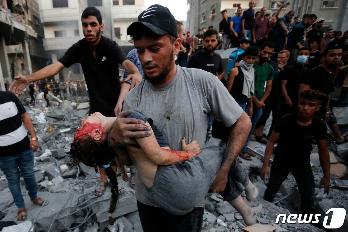 본문 이미지 - 18일(현지시간) 팔레스타인 무장 정파 하마스 기습 공격에 대응한 이스라엘 군의 포격을 받은 가자 지구 데이르 알 발라의 무너진 건물 잔해서 주민이 부상을 당한 어린이를 옮기고 있다. 2023.10.19 ⓒ AFP=뉴스1 ⓒ News1 우동명 기자