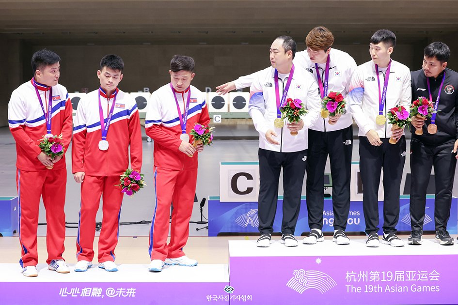 25일 오후 중국 저장성 항저우 푸양 인후 스포츠센터에서 열린 2022 항저우 아시안게임 남자 10ｍ 러닝타깃 단체전 시상식에서 금메달을 목에 건 대한민국 선수들이 2위를 차지한 북한 선수들에게 1위 시상대에 함께 올라 기념촬영 할 것을 권하고 있다. 북한 선수들은 이날 우리 선수들의 제안을 우물쭈물 거리다 끝내 거부했다. 우리 선수들 오른편으로는 함께 1위 단상에 오른 인도네시아 선수&#40;3위&#41;가 이를 의아하게 여기며 북한 선수들을 바라보고 있다. 2023.9.25/뉴스1 민경석 기자